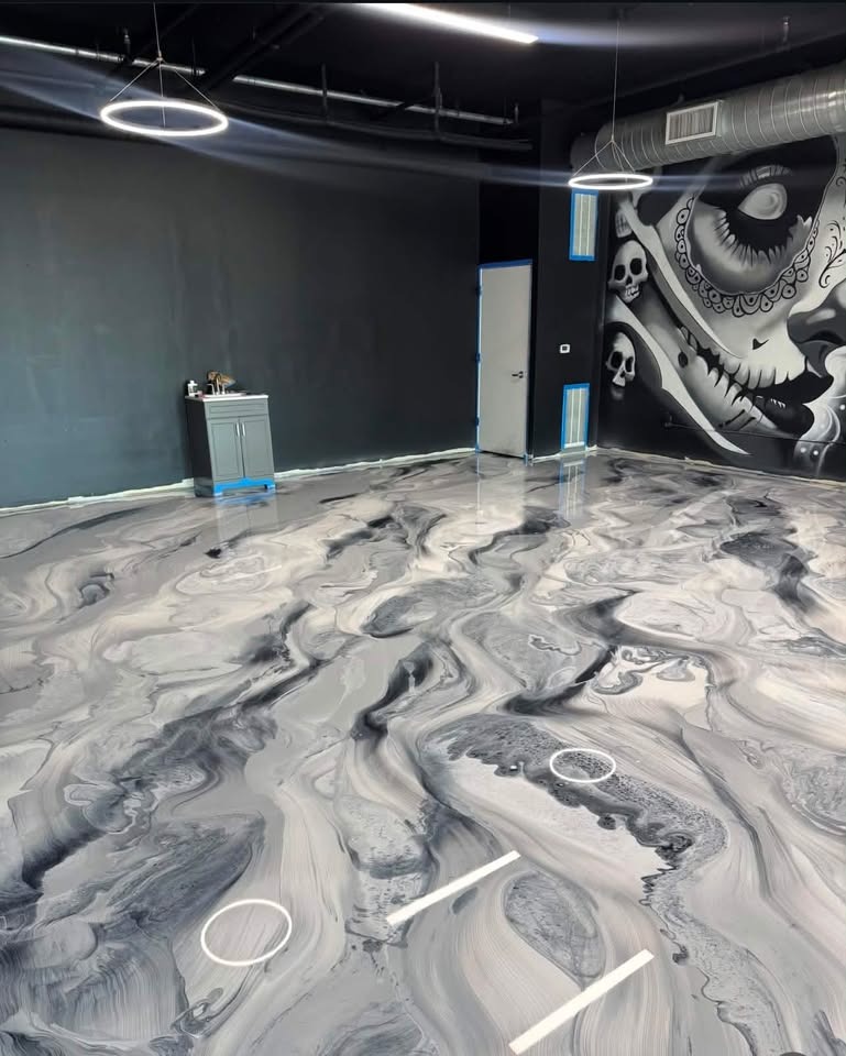 Commercial space with dramatic black and gray swirling metallic epoxy floor and skull mural wall art